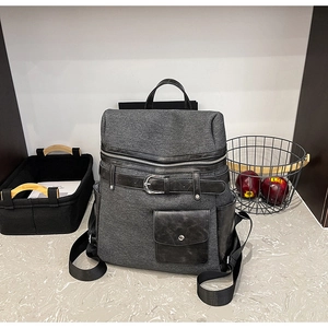 Detail view of the grey textured fabric and black leather contrast stitching on backpack