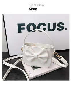 Detail of white crocodile pattern girl handbag featuring a decorative bow and gold metal zip