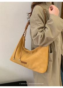 Detail of ginger yellow hobo bag with knotted shoulder strap and matte leather finish