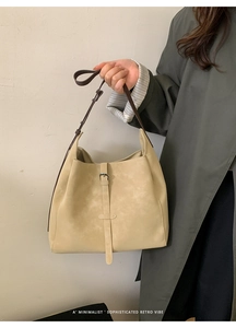 Détail d'un sac seau beige avec bandoulière marron foncé et boucle métallique chic