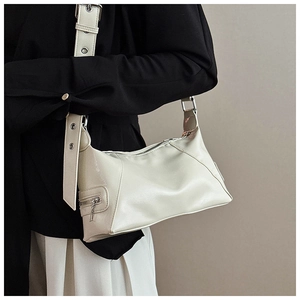 Detail of off-white faux leather tote with metal eyelet strap and side zipper accents