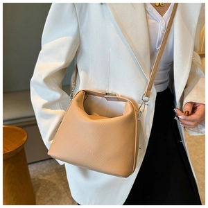 Nahaufnahme der beigen Handtasche aus Leder mit Litschimuster und verstellbarem Gurt