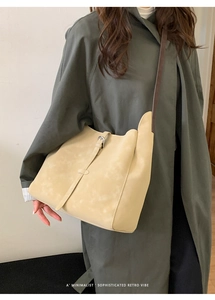 Sac fourre-tout en cuir beige mat avec boucle rétro porté par un mannequin