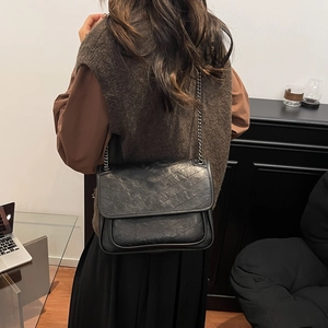 Minimalist black leather crossbody bag with V-quilted pattern and metal chain strap