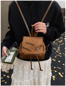 Detail of vintage brown suede backpack featuring decorative leather bows and drawstring