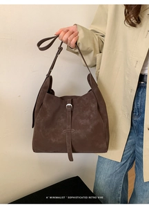 Détail du sac Hobo marron mat avec boucle fine sur un fond minimaliste et épuré
