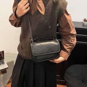 Elegant black quilted shoulder bag with chain strap shown on model for a stylish look