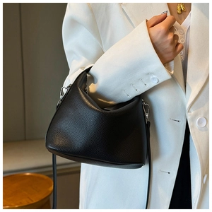 Detail der schwarzen Handtasche mit Lychee-Maserung kombiniert mit einem weißen Blazer