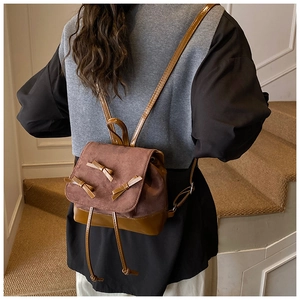 Detailed view of brown bow backpack with suede texture and leather trim on model