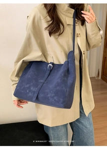 Détail d'un grand sac cabas en daim bleu avec boucle rétro et finitions métalliques sobres