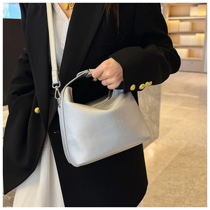 Detail einer silbernen Handtasche aus Leder mit Litschistruktur und Metallreißverschluss
