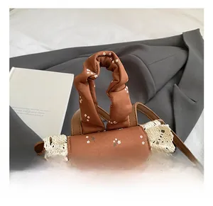 Détail d'un sac à dos floral marron avec bordure en dentelle blanche et nœud décoratif