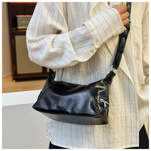 Detail of black glossy PU leather tote bag with silver eyelet wide strap and metallic zipper