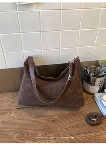 Detail of brown suede tote bag with side knot accent and spacious interior lining