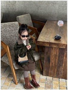 Detail view of khaki and black chain handbag paired with a vintage kids' olive jacket