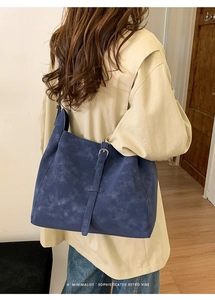 Détail d'un grand cabas vintage bleu mat porté avec un trench-coat beige élégant