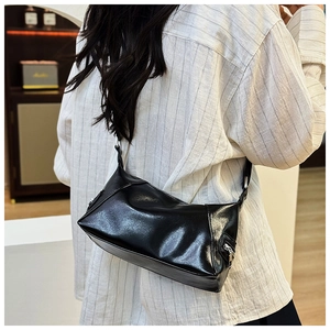 Polished black PU leather shoulder bag with side zipper detail worn by a model