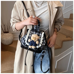Detail of checkered toddler backpack with white lace ruffles and a cute 3D teddy bear charm