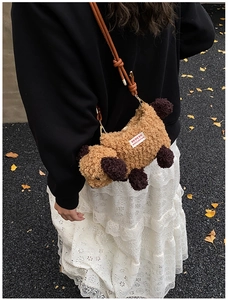 Détail du sac à bandoulière chiot en peluche avec étiquette Merry Christmas tissée