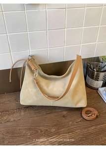 Detail of beige suede hobo bag featuring brown leather strap and silver chain accent