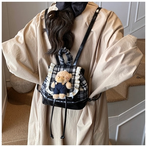 Detail of checkered toddler backpack featuring lace trim and a cute plush bear charm