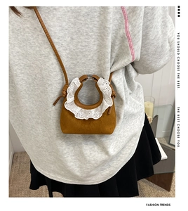 Détail d'un mini sac bandoulière en daim marron avec d'élégantes finitions en dentelle
