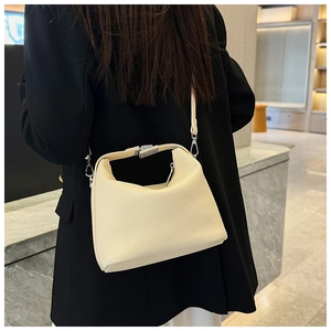 Detail der cremefarbenen Ledertasche in Halbmondform mit Narbenleder auf schwarzem Blazer