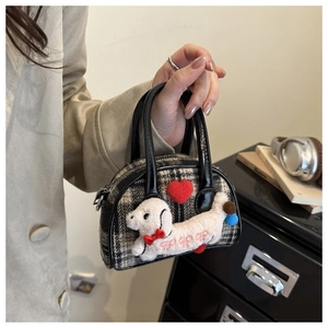 Détail d'un mini sac à main à carreaux avec un chiot en peluche et une poignée en cuir noir