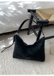 Detail of black suede hobo bag featuring zip closure and minimalist brand logo