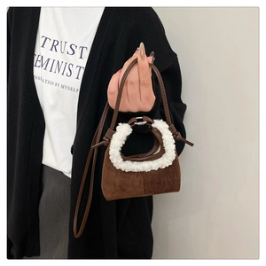Close-up of brown suede mini bag featuring soft white faux fur trim and crossbody strap