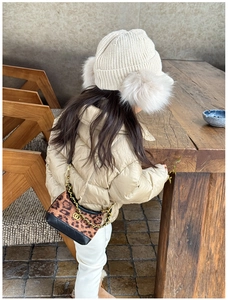 Detail view of leopard print plush bag with gold chain strap and quilted jacket