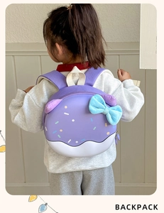 Vista posteriore di un bambino con zaino a ciambella viola con fiocco in peluche e spallacci