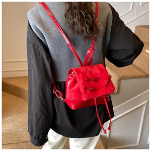 Detail of red mini backpack featuring leather splicing and delicate ribbon bow decorations