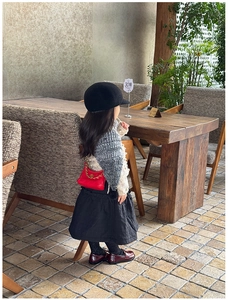 Child fashion look with red leopard chain bag and grey knitted cape on outdoor cafe background