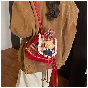 Toddler backpack with lace trim and plush bear charm shown on a child's shoulder