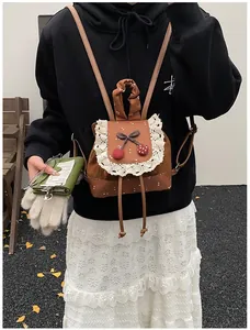 Détail d'un sac à dos d'école marron avec dentelle, accents cerises et pois blancs