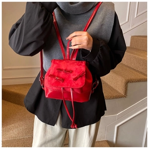 Detail of red mini backpack with three bow decorations and stylish drawstring closure