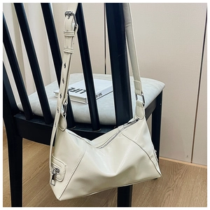 Detail of a creamy PU leather baguette bag featuring an eyelet adjustable shoulder strap