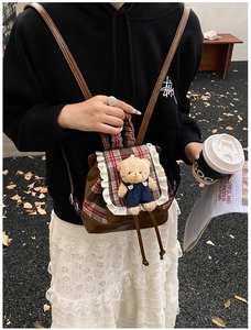 Detail of cute bear backpack with red plaid pattern and lace edges on a young child