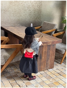 Rear view of a child wearing a red quilted mini crossbody bag with a gold chain strap