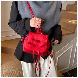 Detail of red bow mini backpack showing glossy patent leather and matte suede texture