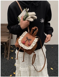 Détail d'un sac à dos en daim marron avec dentelle blanche et accents cerise 3D