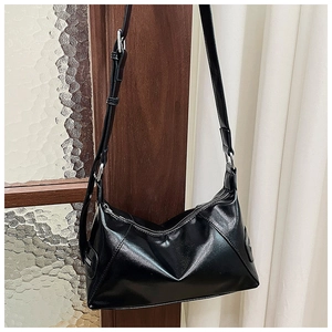 Detail of black glossy leather tote bag with silver metal zipper and textured finish