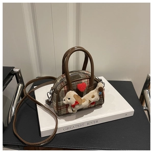 Détail du chiot en peluche et du cœur sur le sac à main en tweed à carreaux rouges