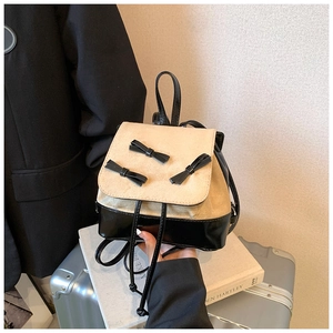 Detail of cream matte flap with black bows on a two-tone leather mini backpack