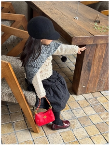 Detail of red quilted leather kid's bag featuring gold chain and double ring hardware