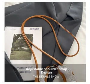 Détail de la bandoulière réglable en cuir marron avec bordure en dentelle blanche d'un sac à main