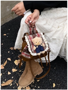 Detail of vintage children's backpack with red plaid pattern and cute teddy bear pendant