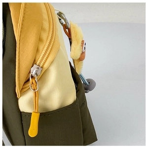 Detail of ripstop fabric texture and cute yellow plush charm on kid shoulder bag