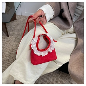 Nahaufnahme einer kleinen roten Wildleder-Handtasche mit süßem weißen Spitzenbesatz